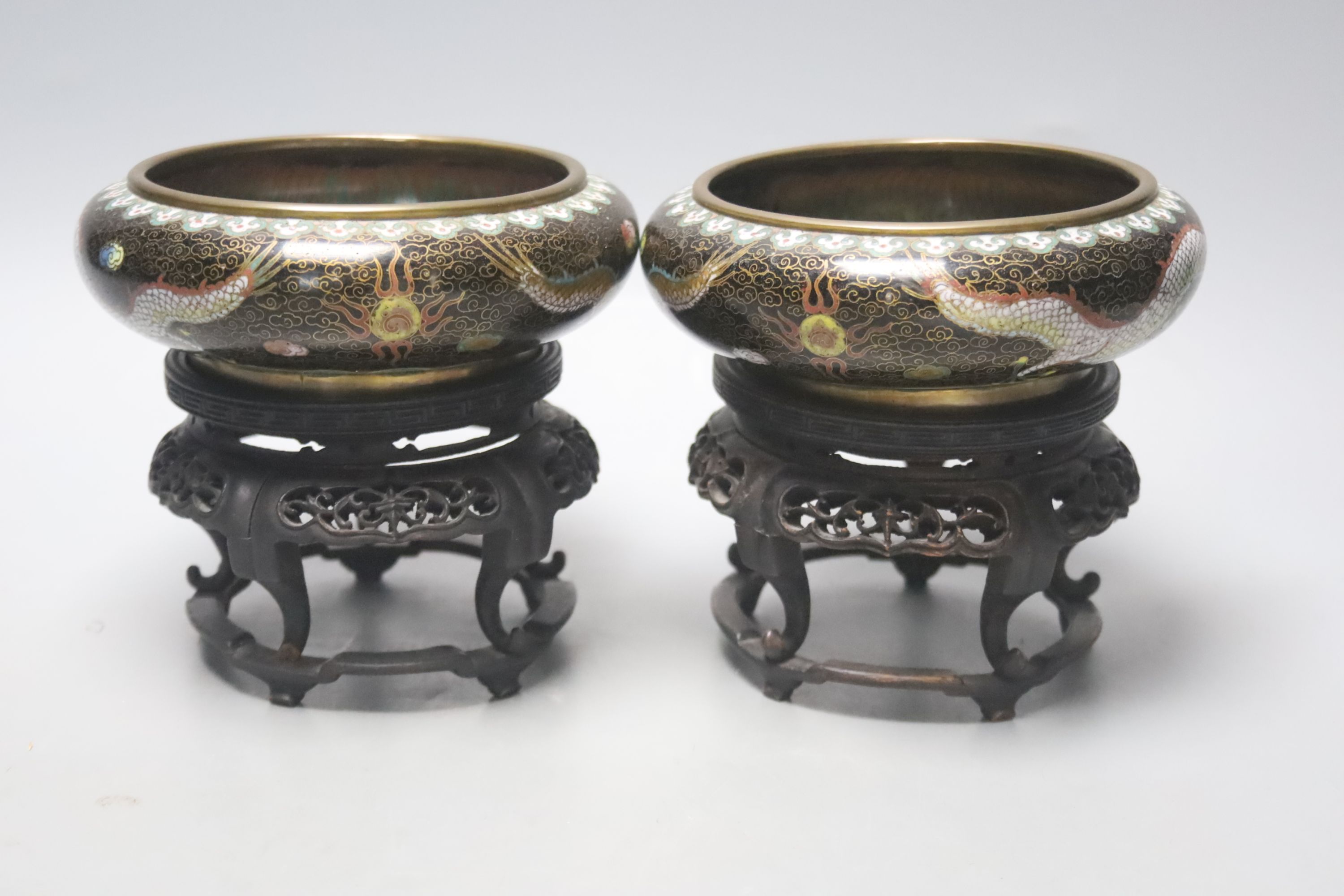 A pair of Chinese cloisonne enamel small 'dragon' bowls, wood stands